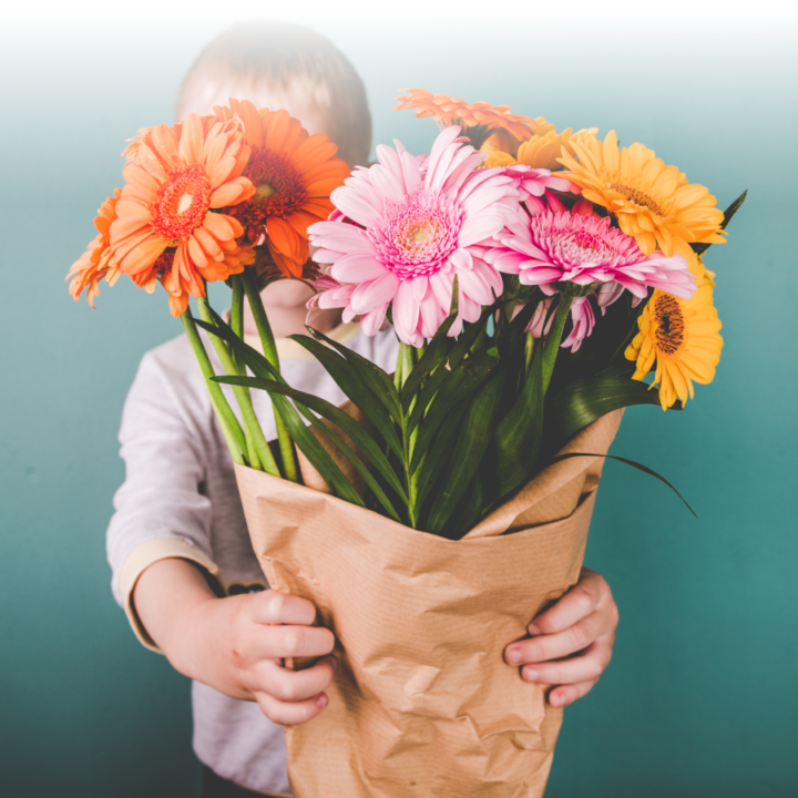 boy holding flowers in front of his face